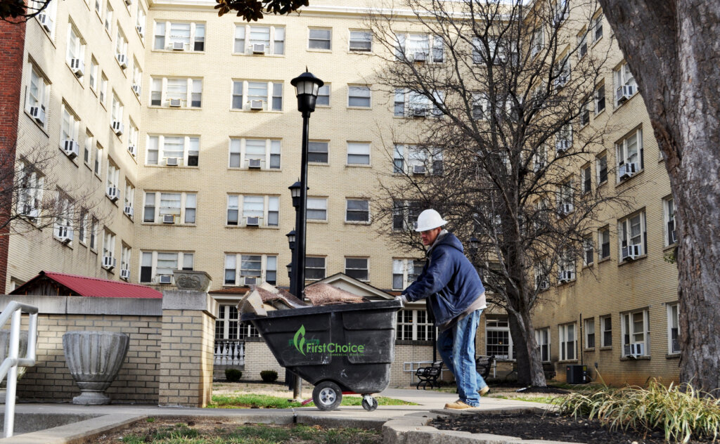 Man in construction hat pushing a bin of construction material