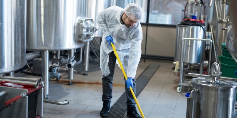 Man in safety gear mopping an industrial workspace demonstrating our industrial cleaning services
